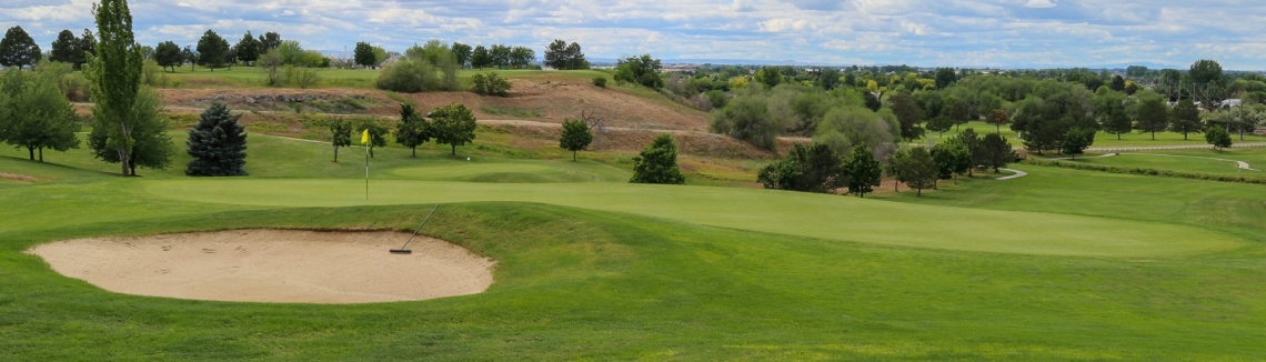 Wide view of the green and bunkers at Ridgecrest Golf Club under a blue sky.