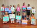 Children holding up their paintings at the children's art workshop