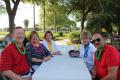 residents sitting at a long table in the beautiful garden area at the annual community barbeque